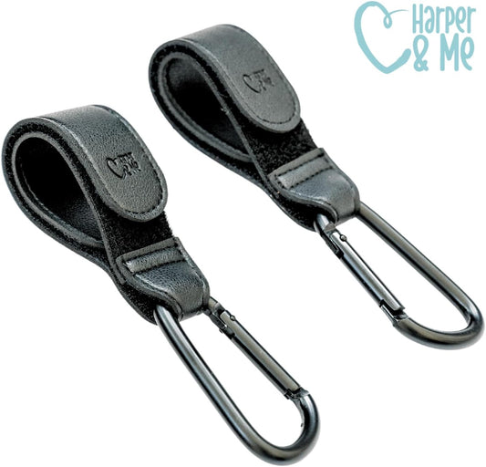 Two black leather straps with carabiners on a white background, featuring the brand 'Harper & Me'.
Harper & Me universal buggy clips for prams and strollers – Thursday’s Child Rental