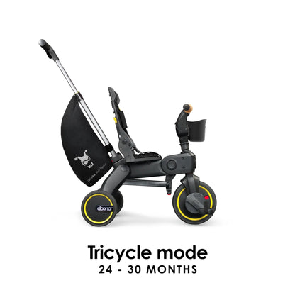 Doona Liki Trike S5 in Midnight Black shown in full tricycle mode with pedals and handlebar engaged — perfect for toddlers gaining independence, available from Thursday’s Child Rental.
